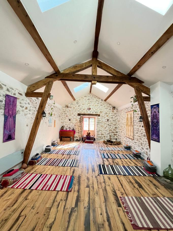 Sunlit yoga studio at Viveka, with wooden beams, stone walls and mats laid out for practice