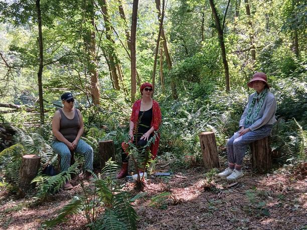 People sitting together in a shaded woodland clearing at Viveka